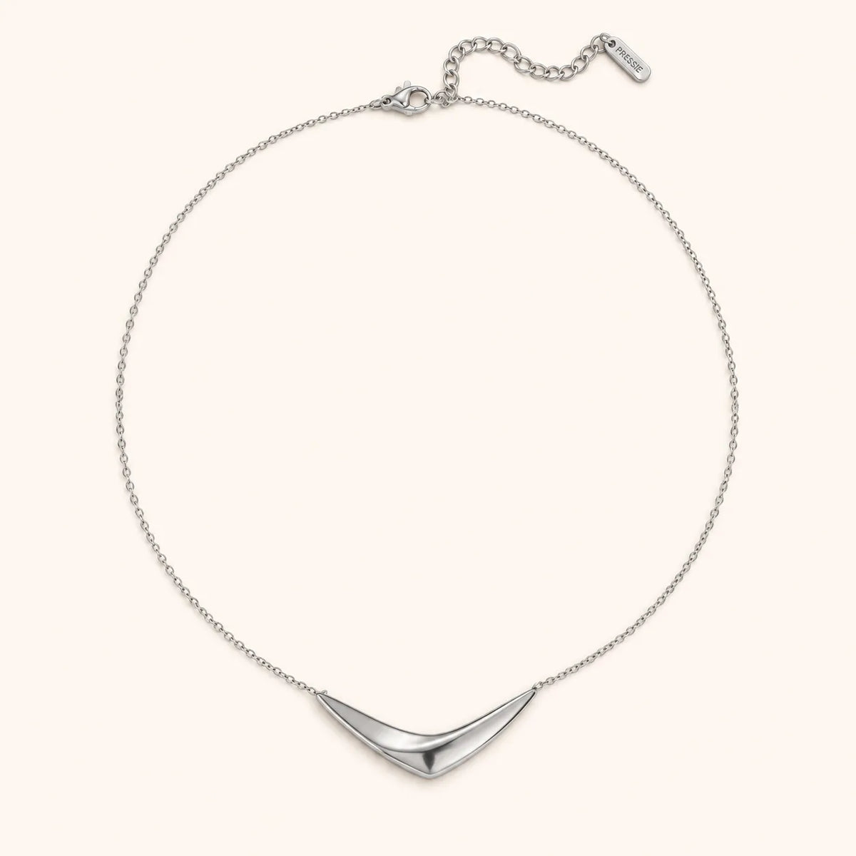 A silver chain necklace with a polished, curved chevron pendant, displayed on a clean, solid cream background.