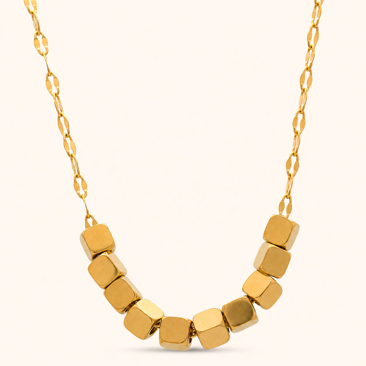 Gold necklace with hexagonal beads on a light beige background