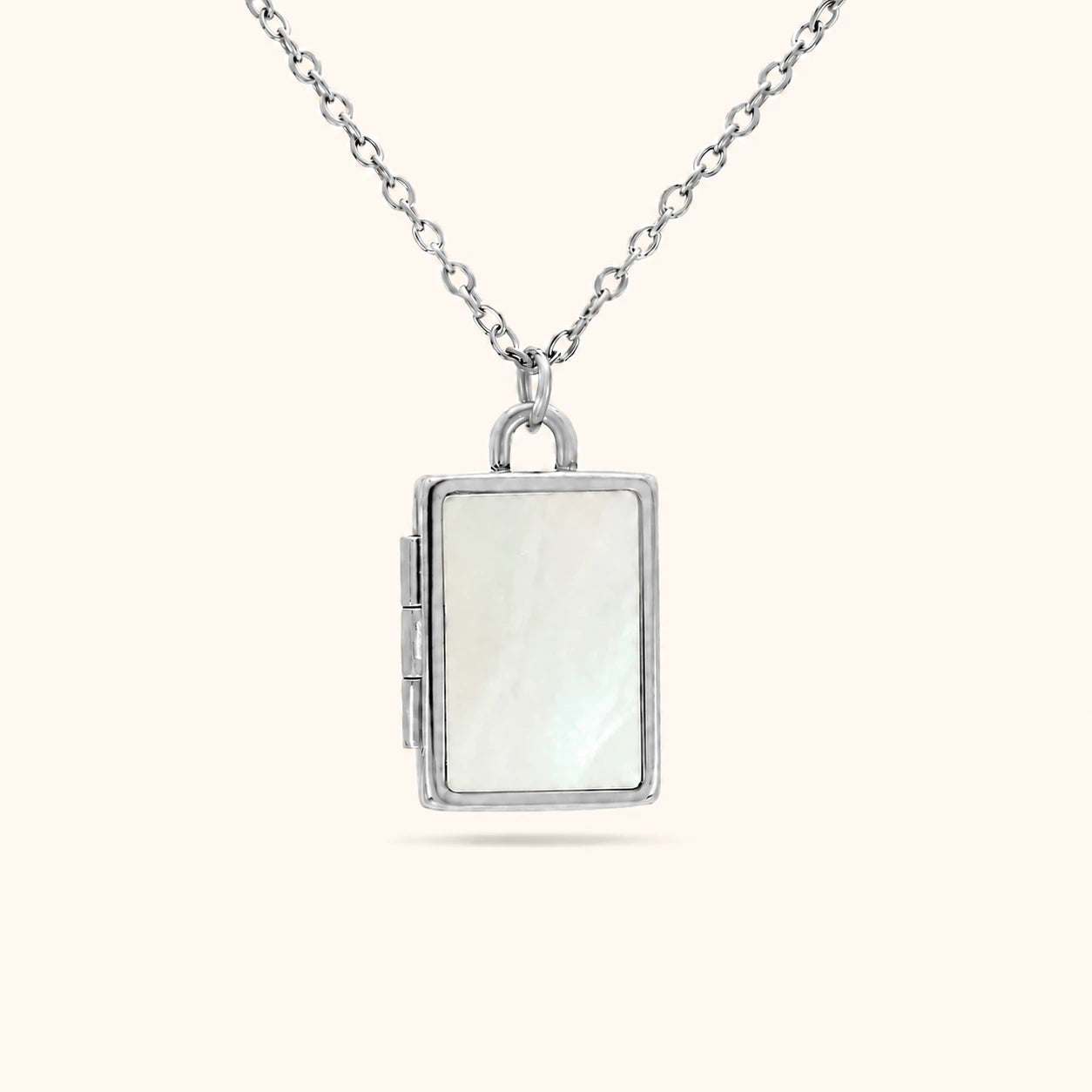 Silver locket necklace with a white stone on a white background