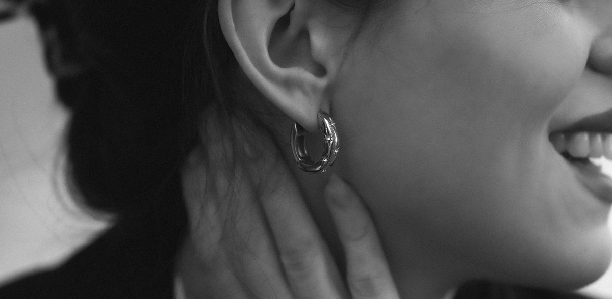 Black-and-white close-up of a polished hoop earring worn on the ear