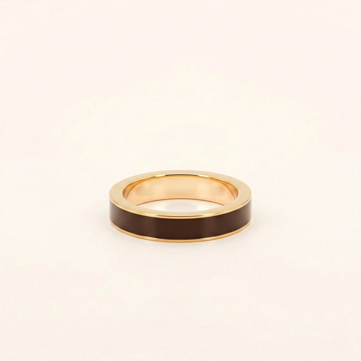 Gold ring with a dark brown band on a light beige background