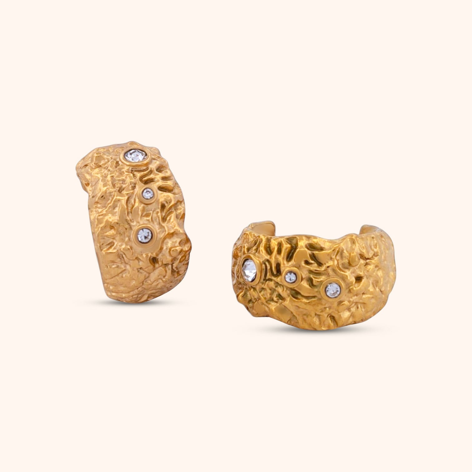 Close-up of the Celeste Hoops, gold hoop earrings featuring a textured surface and sparkling crystal accents.