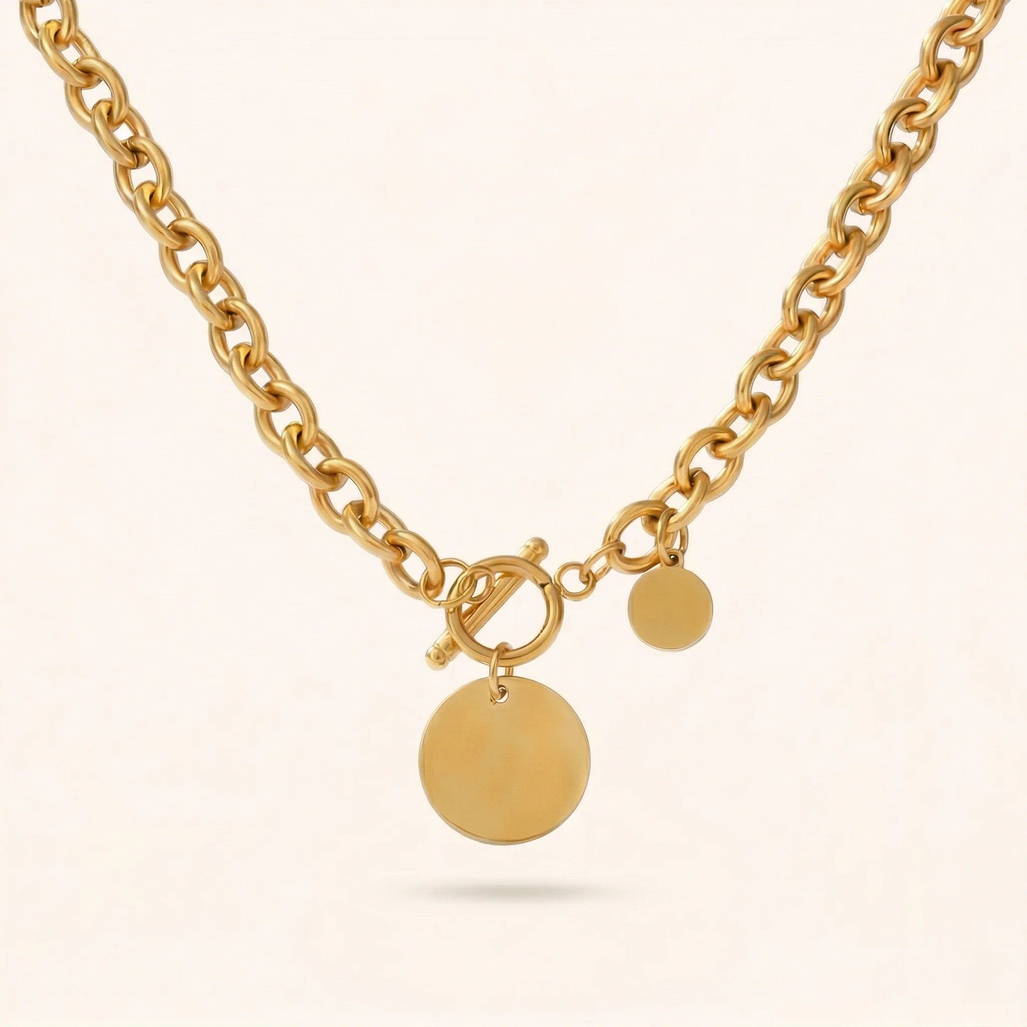 Gold necklace with round pendants on a light beige background