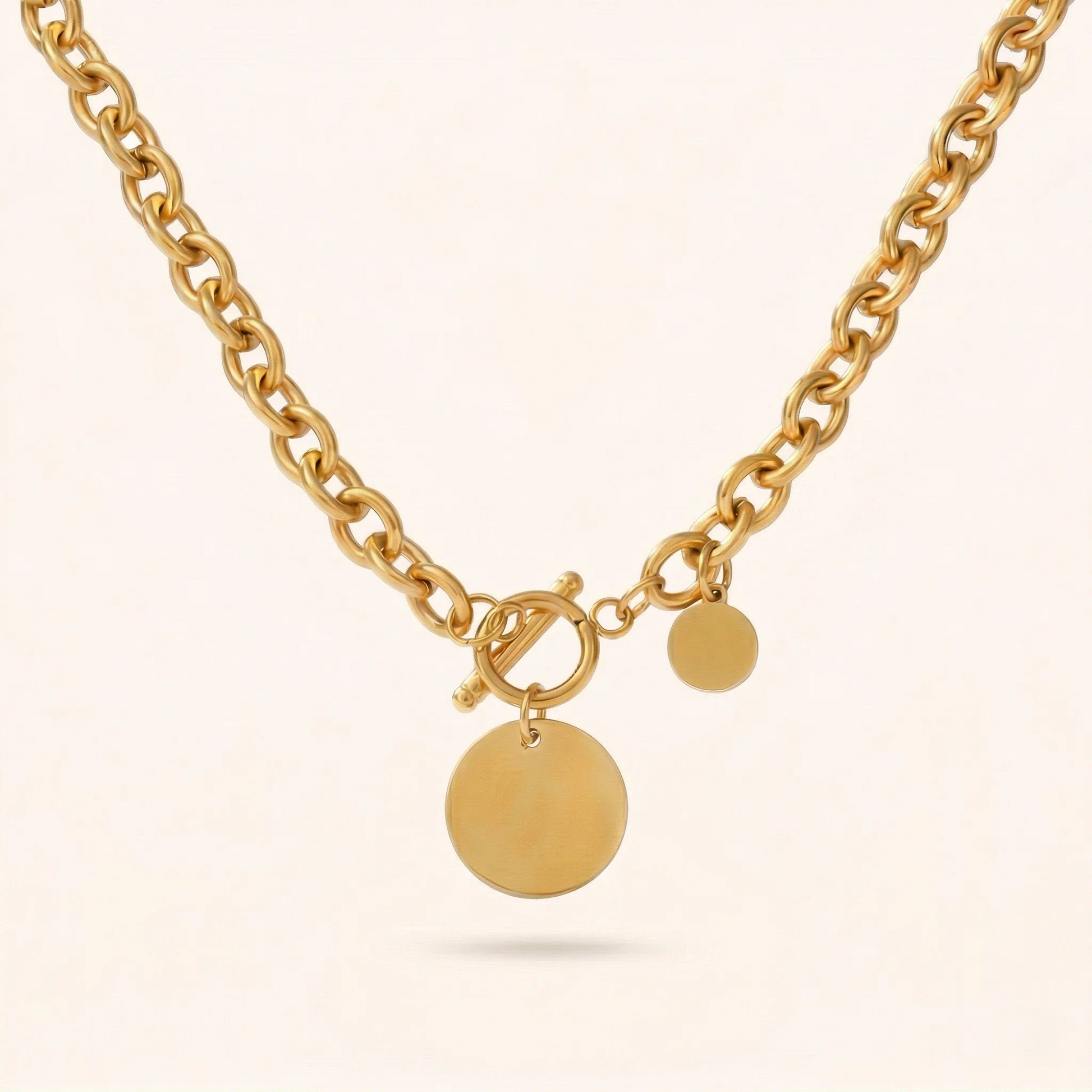 Gold necklace with round pendants on a light beige background