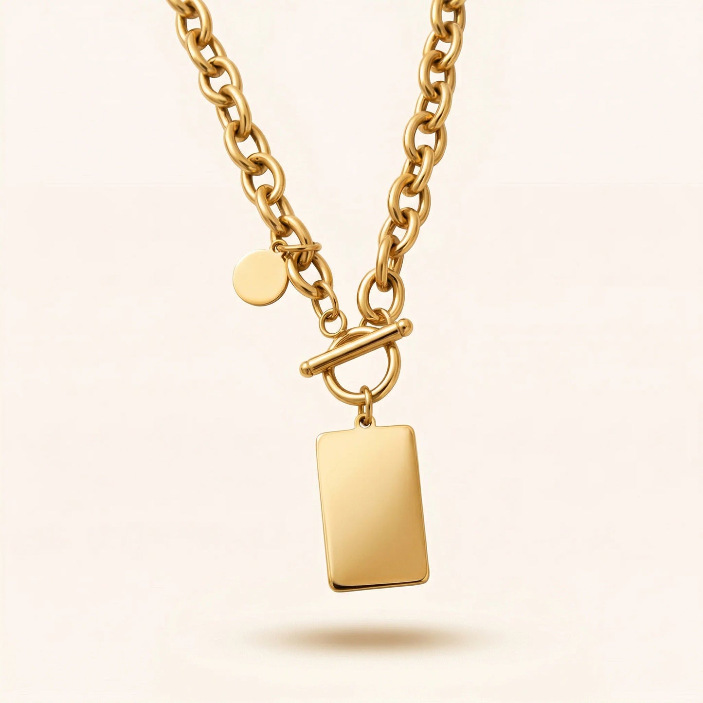 Gold necklace with a rectangular pendant on a beige background
