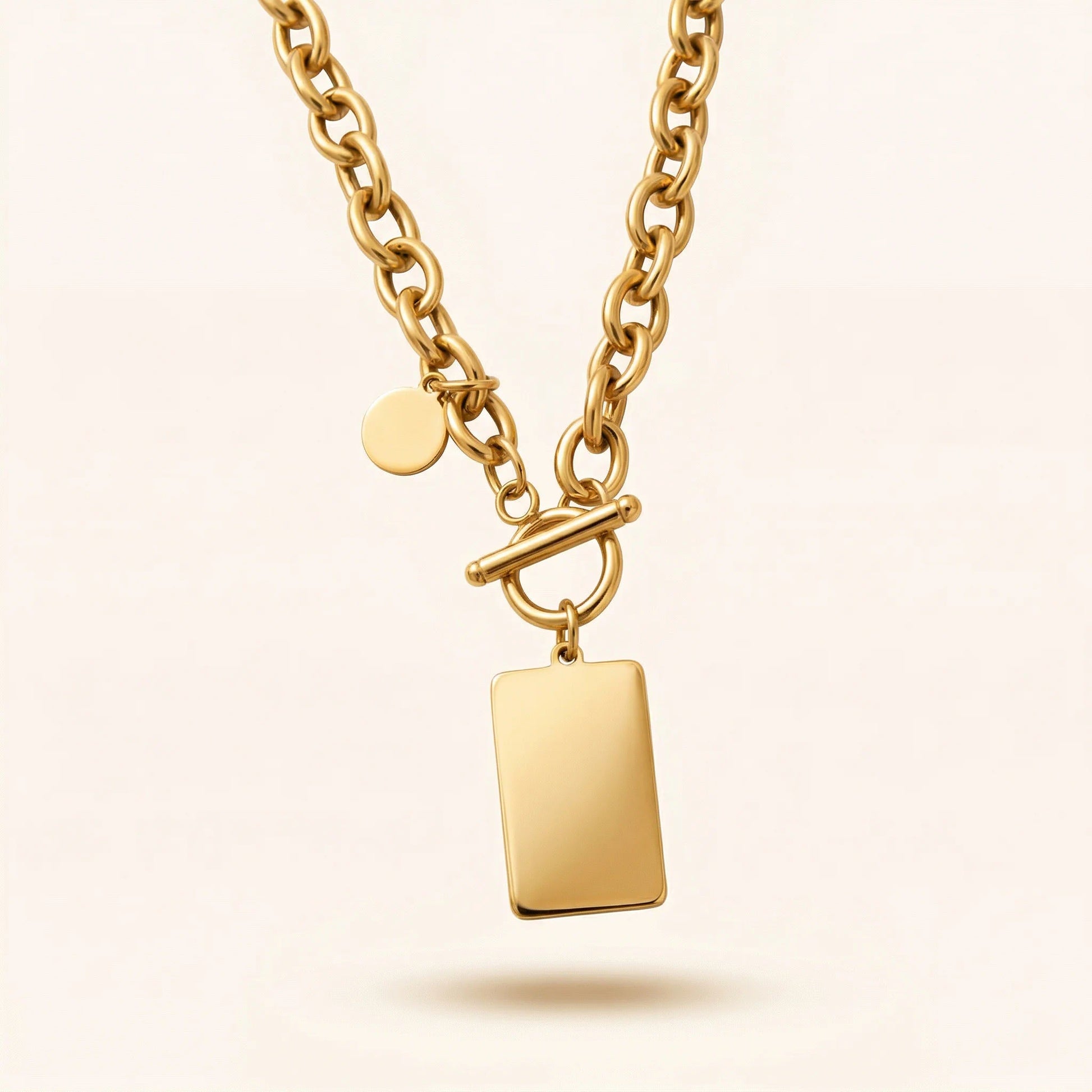 Gold necklace with a rectangular pendant on a beige background