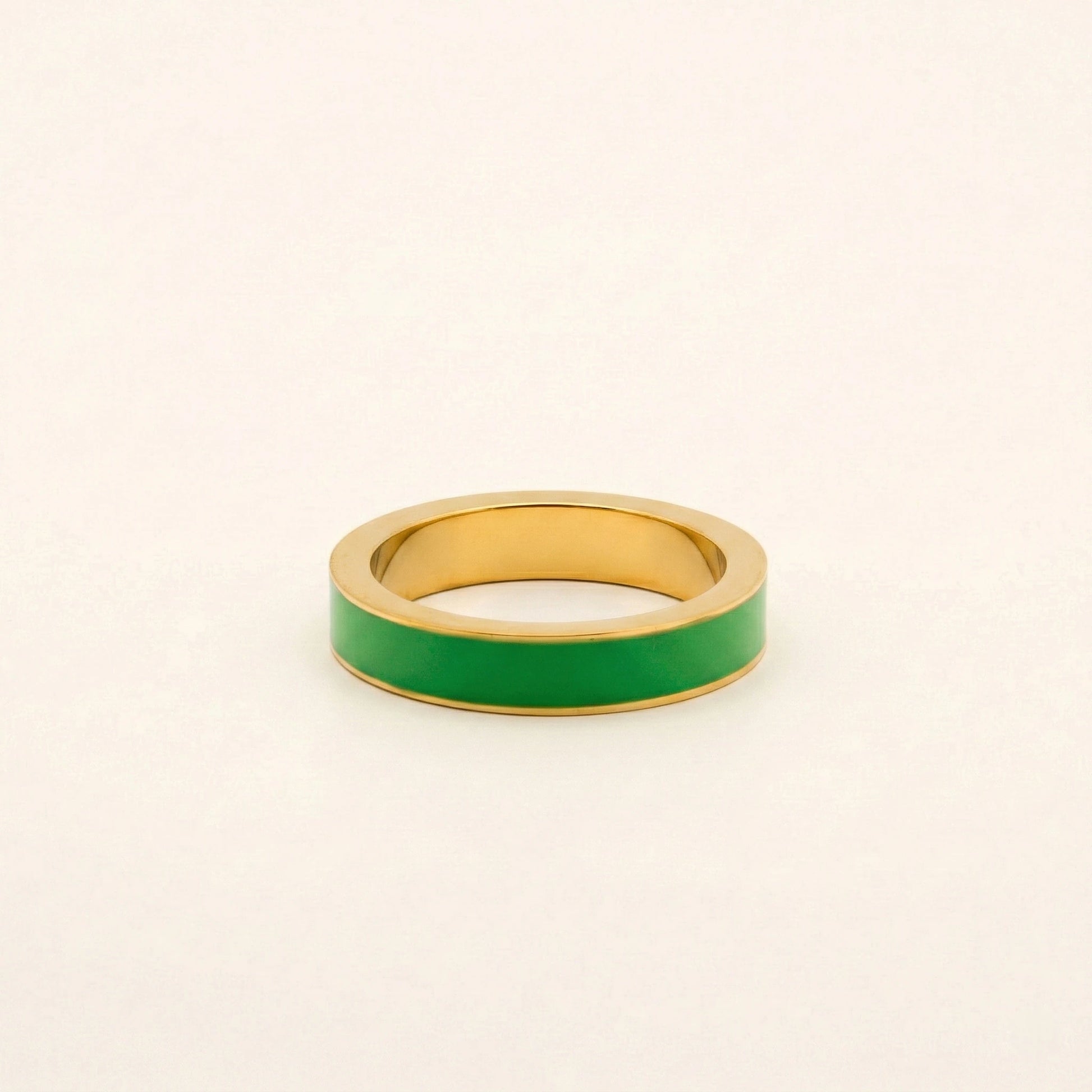 Gold ring with a green band on a beige background