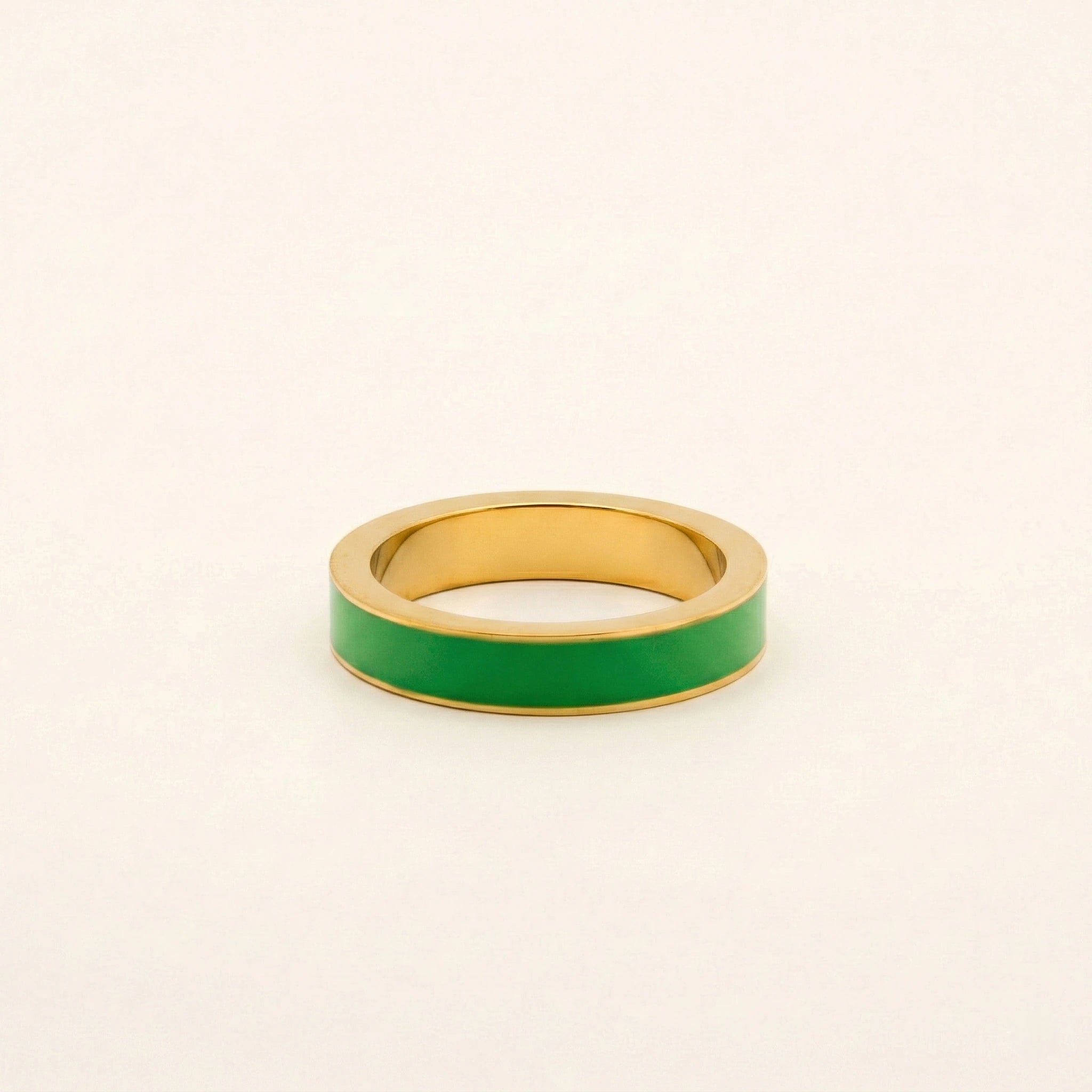 Gold ring with a green band on a beige background