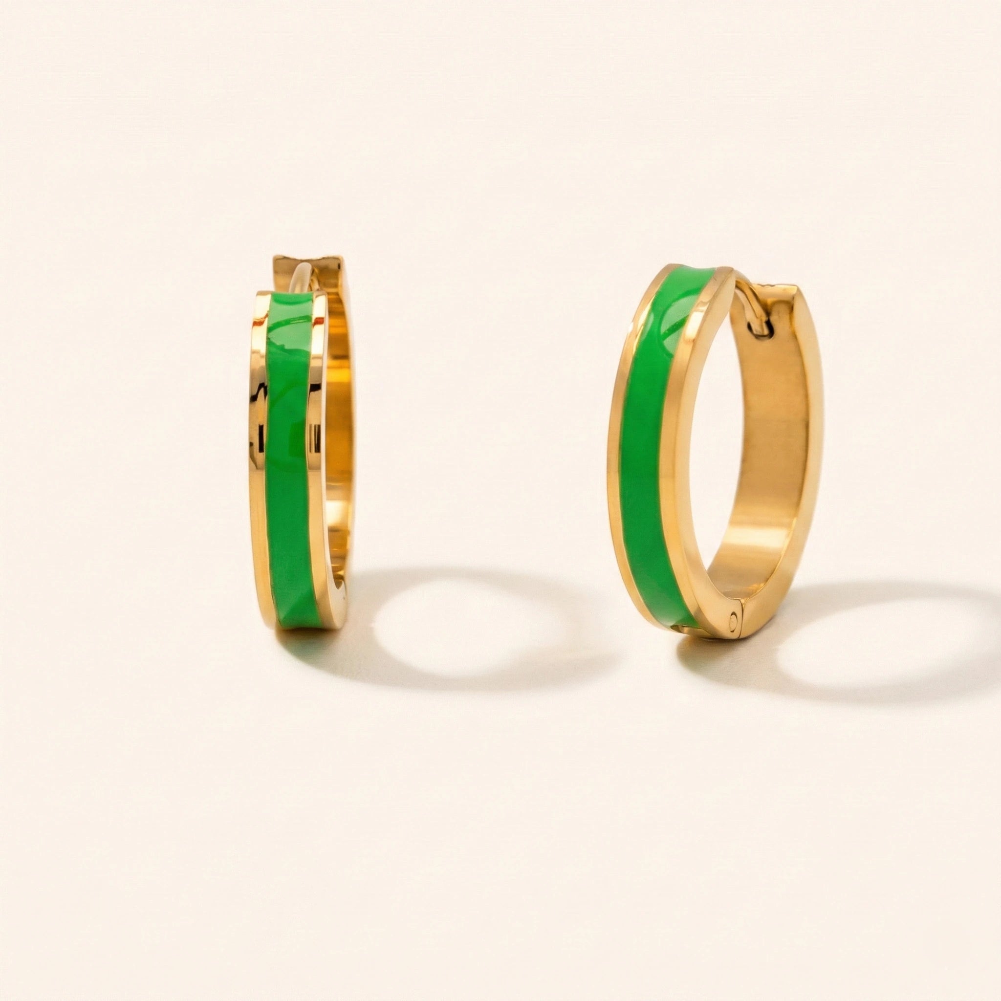 Gold hoop earrings with green interior on a light beige background