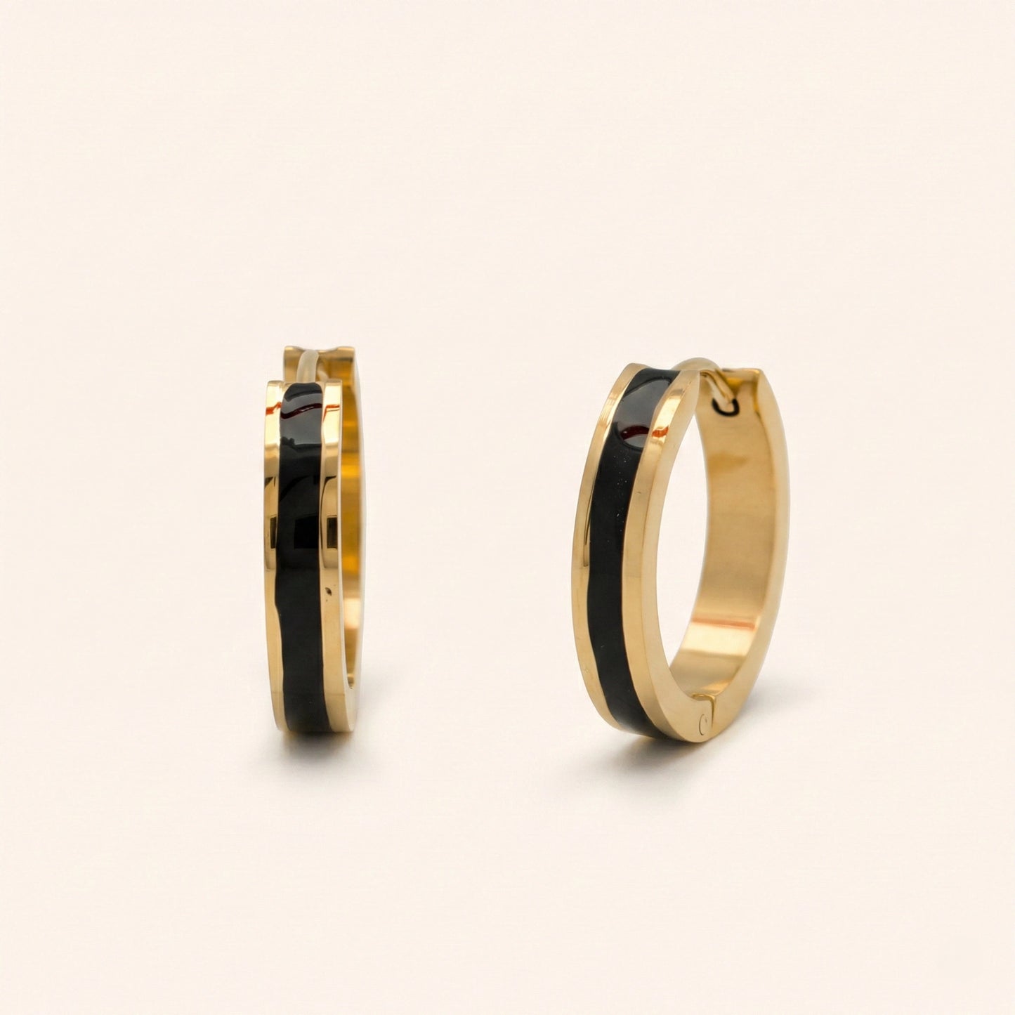 Gold hoop earrings with black interior on a beige background