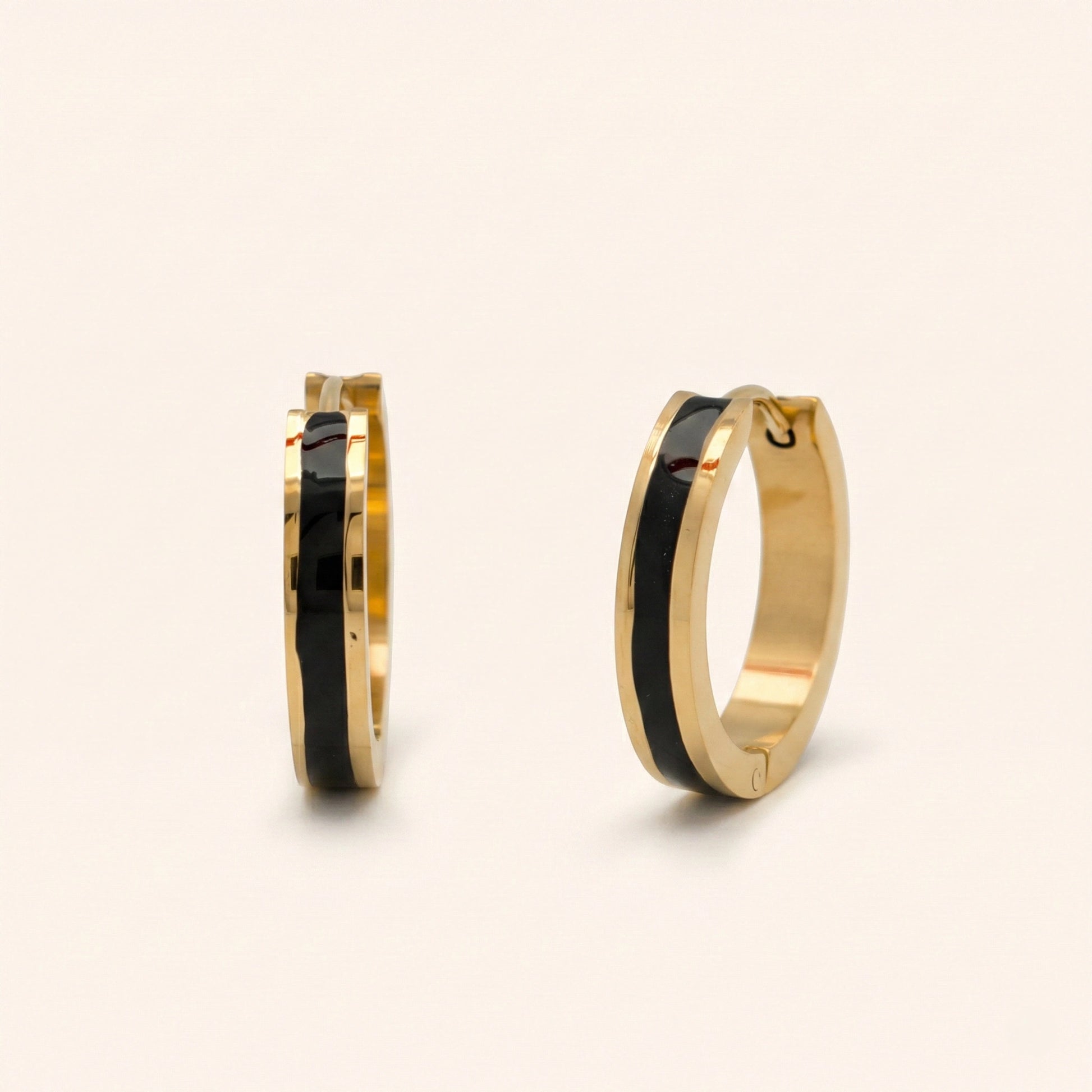 Gold hoop earrings with black interior on a beige background