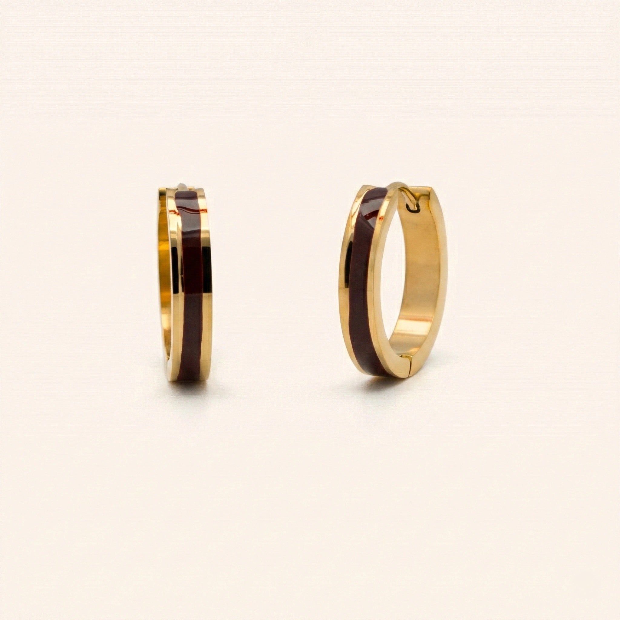 Gold hoop earrings with black interior on a beige background