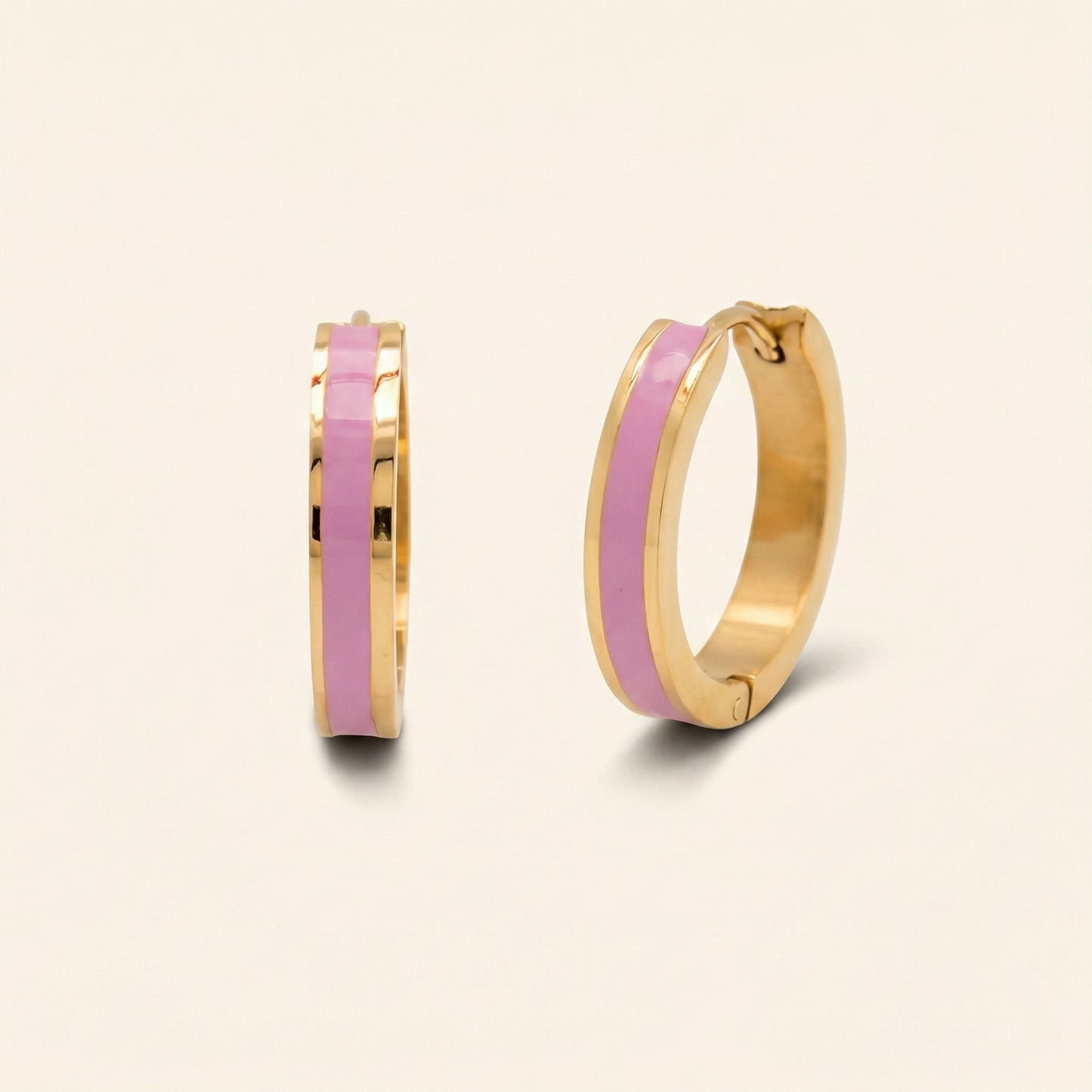 Gold hoop earrings with pink interior on a light beige background