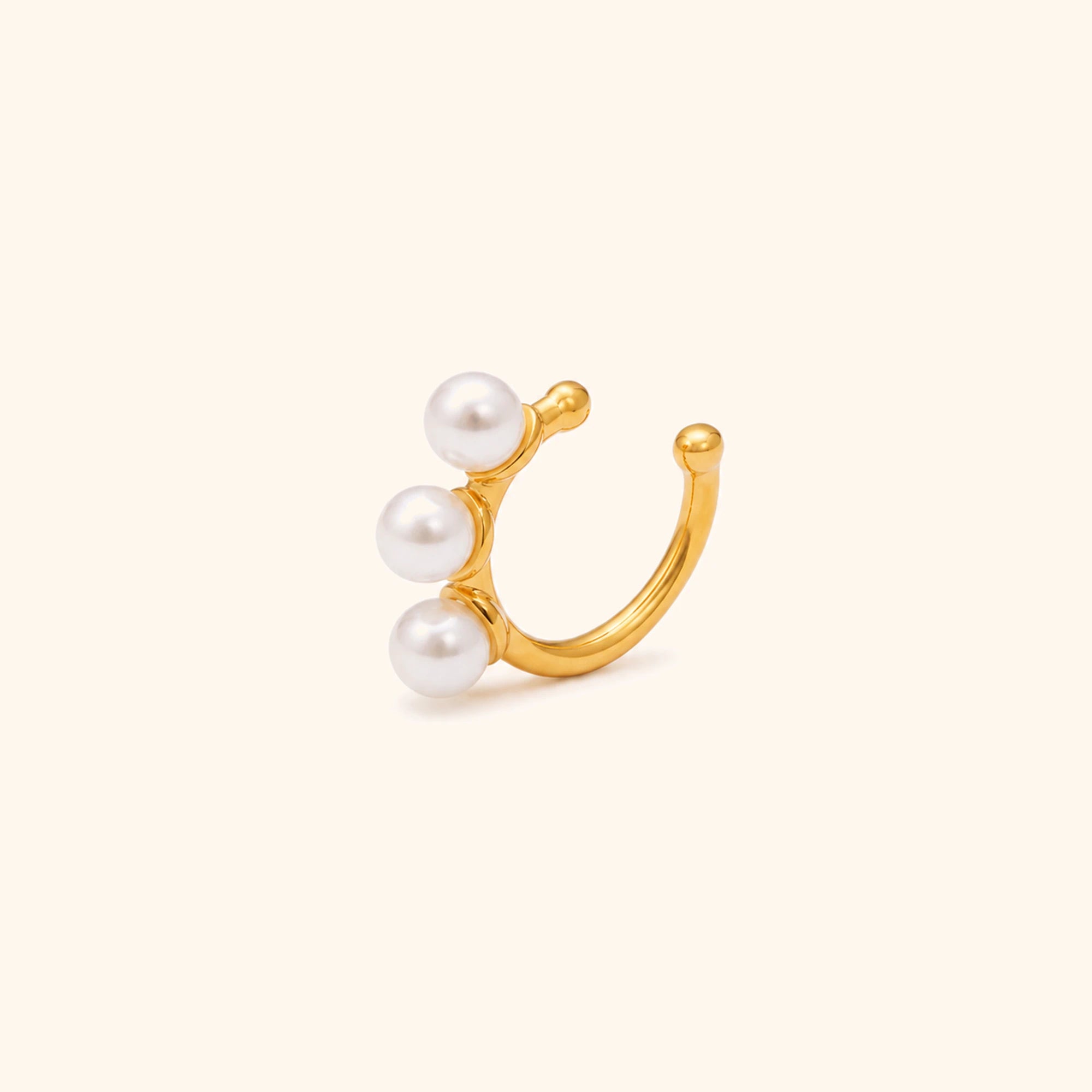Gold earing cuff with three pearls on a white background