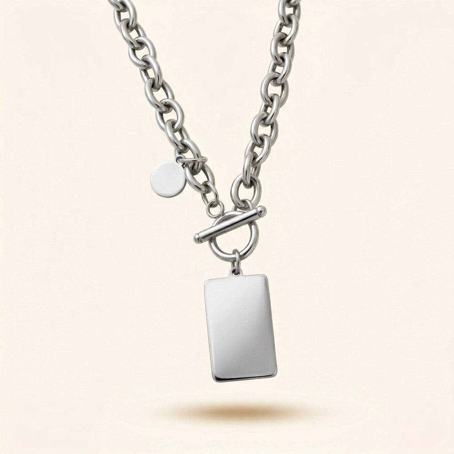 Silver necklace with a rectangular pendant on a light beige background
