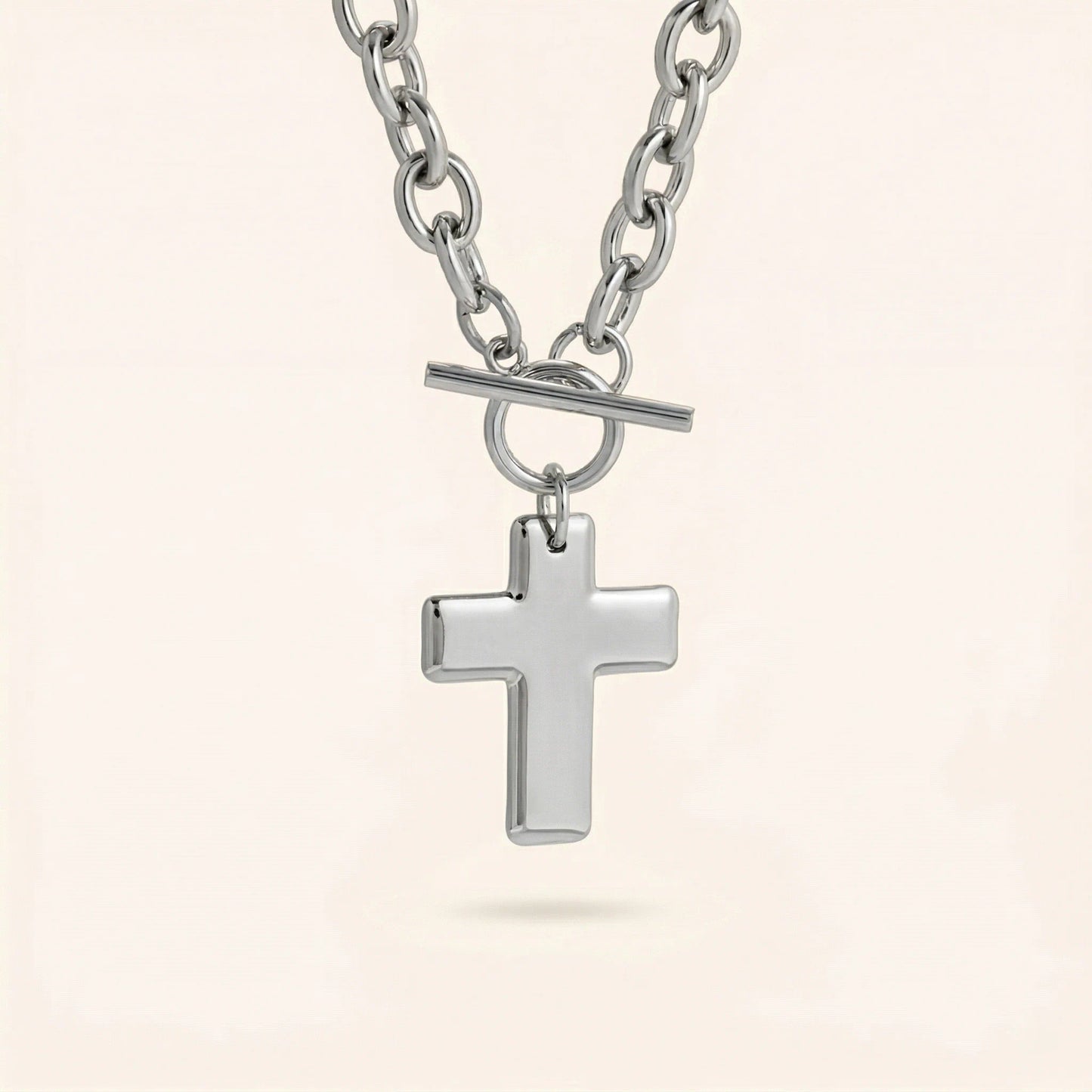 Silver cross pendant necklace on a light beige background