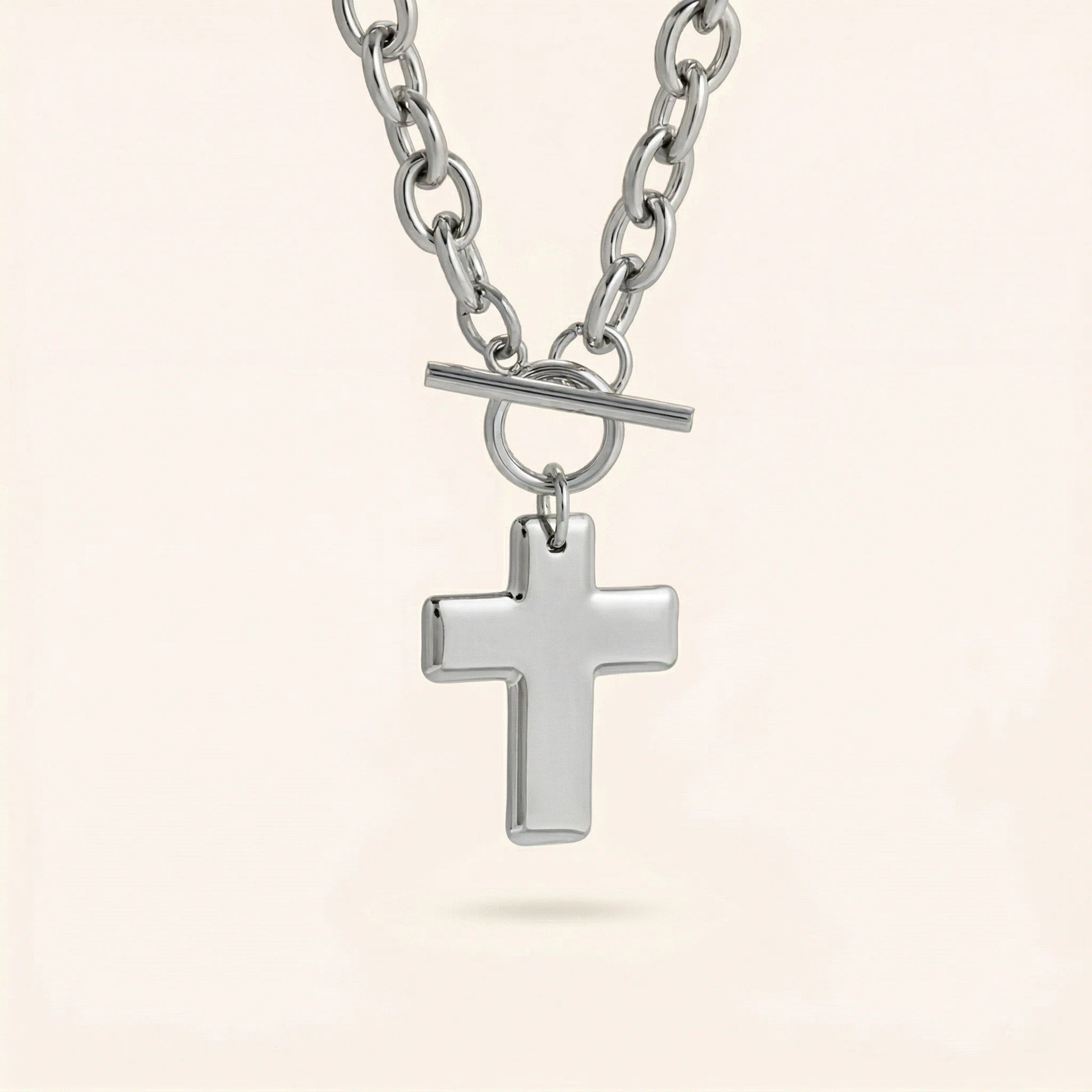 Silver cross pendant necklace on a light beige background