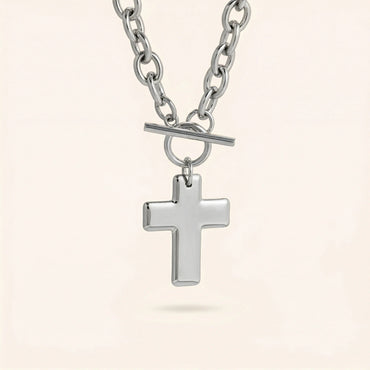 Silver cross pendant necklace on a light beige background
