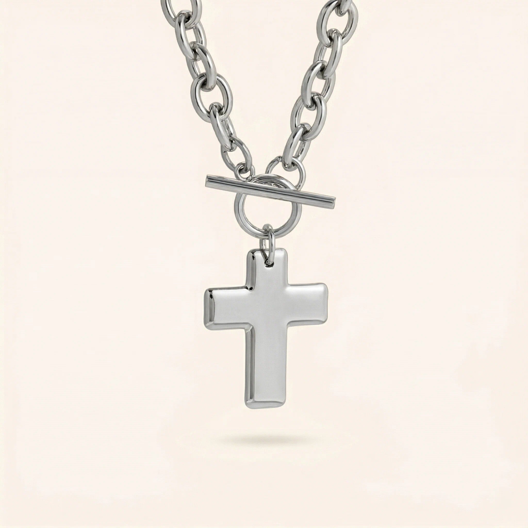Silver cross pendant necklace on a light beige background