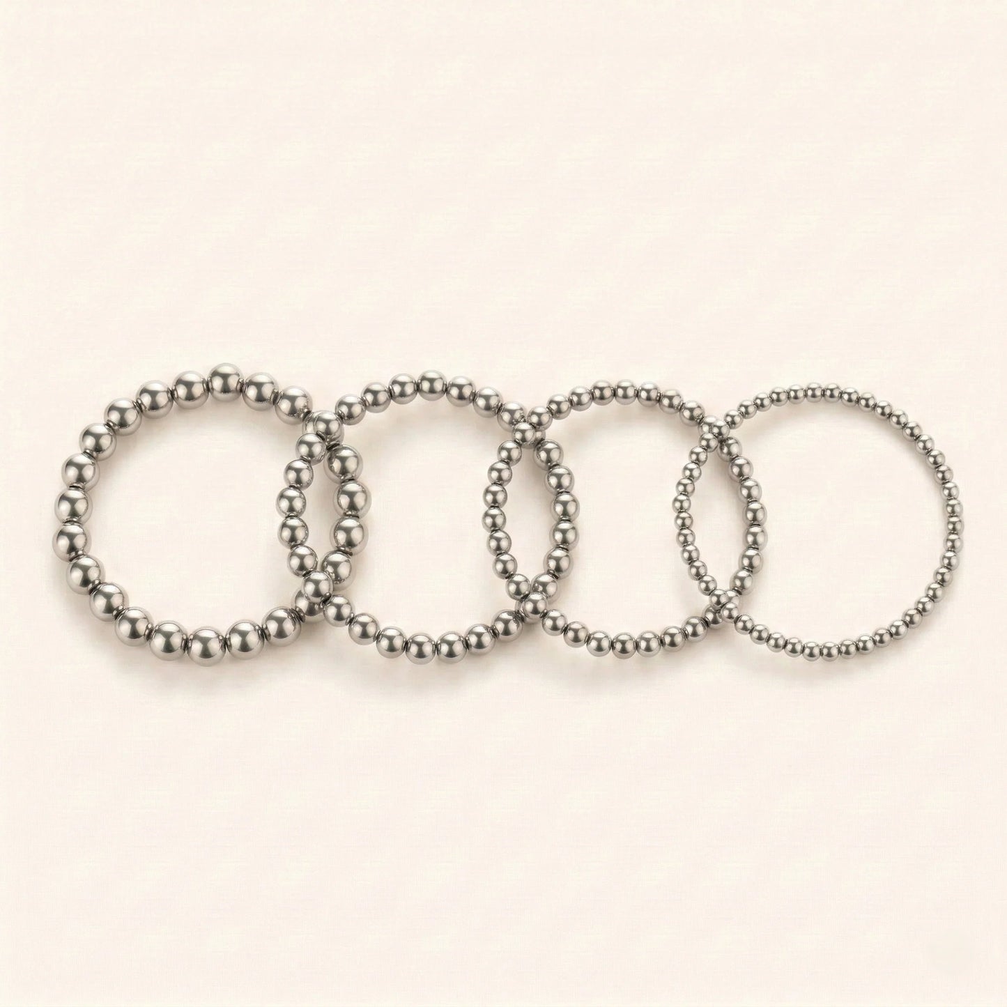 Set of five silver beaded bracelets on a light beige background