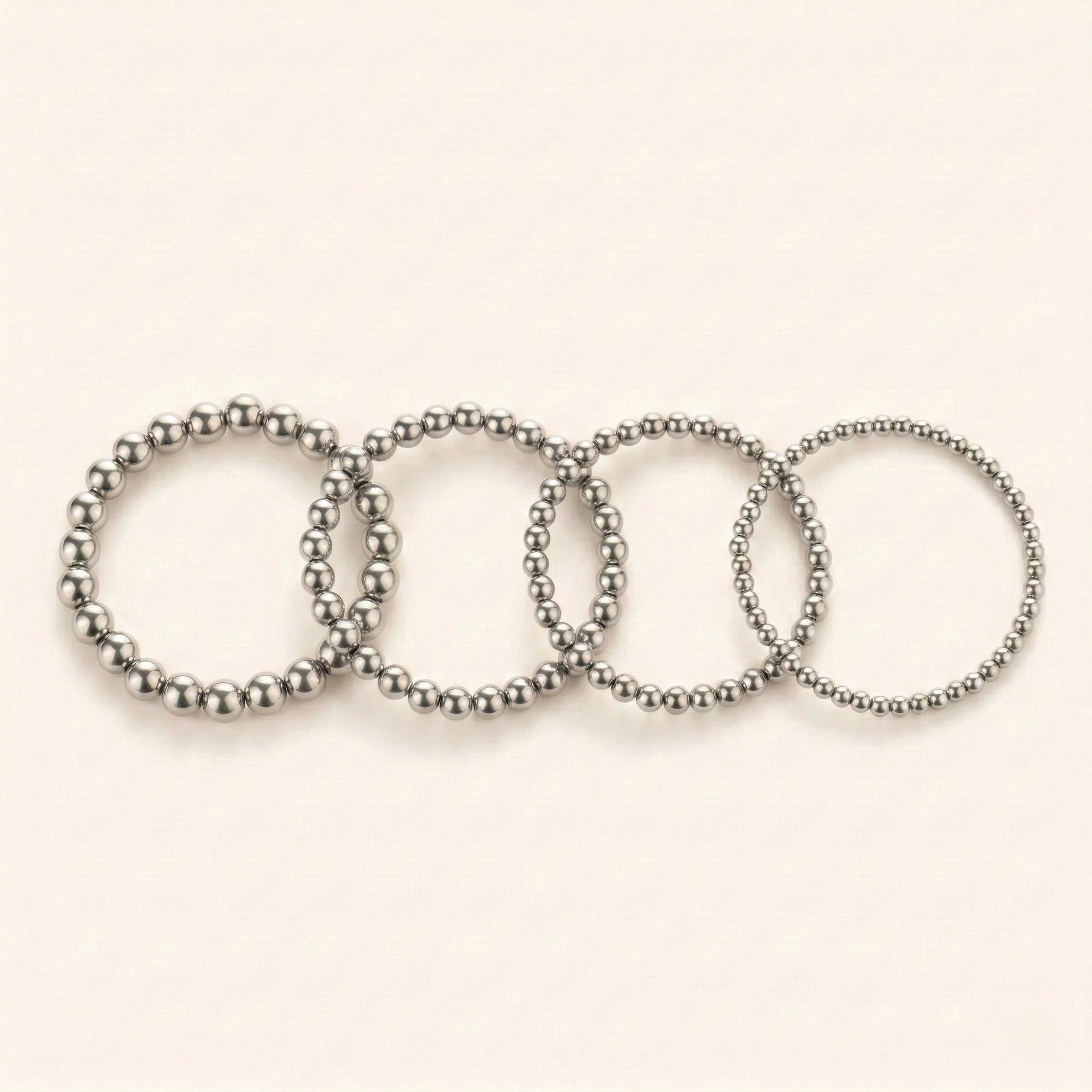 Set of five silver beaded bracelets on a light beige background
