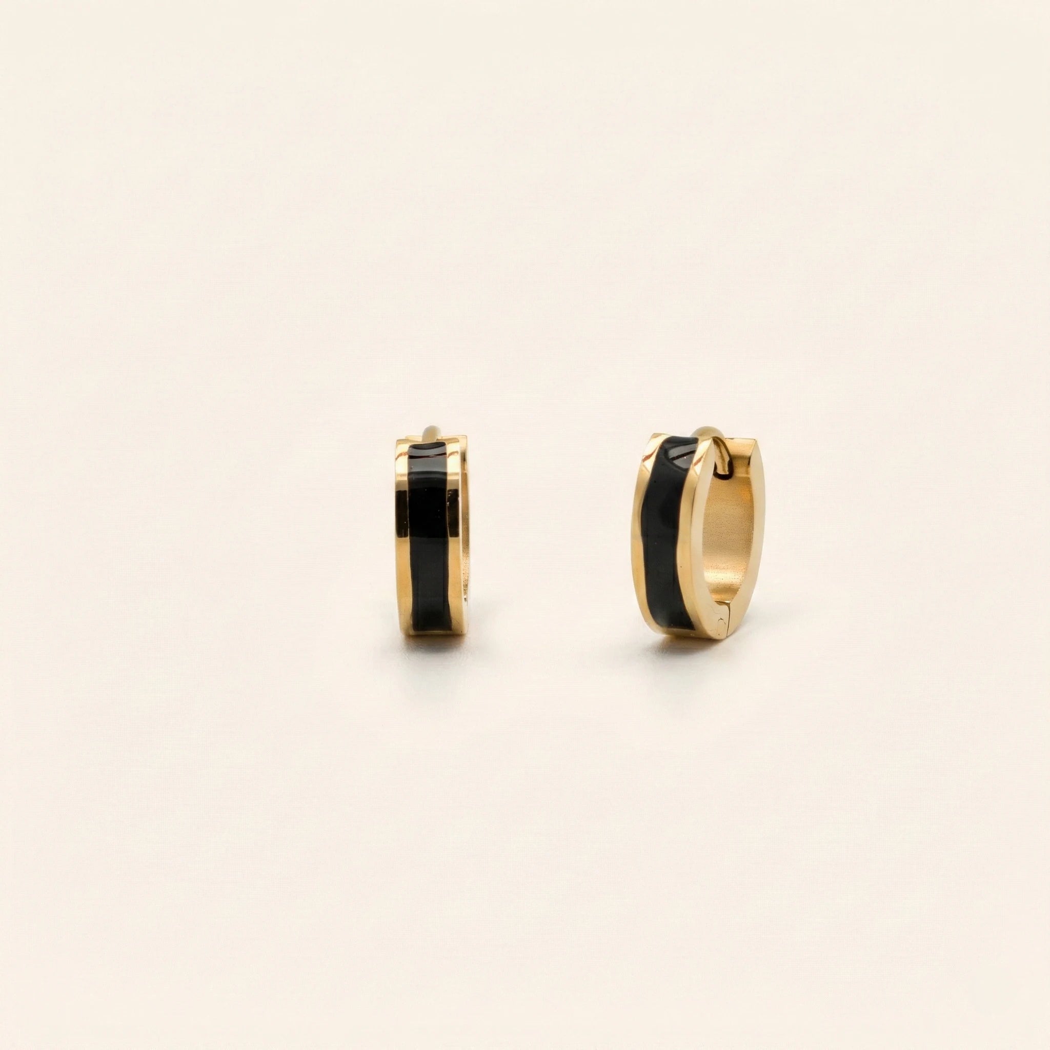 Gold hoop earrings with black centers on a beige background