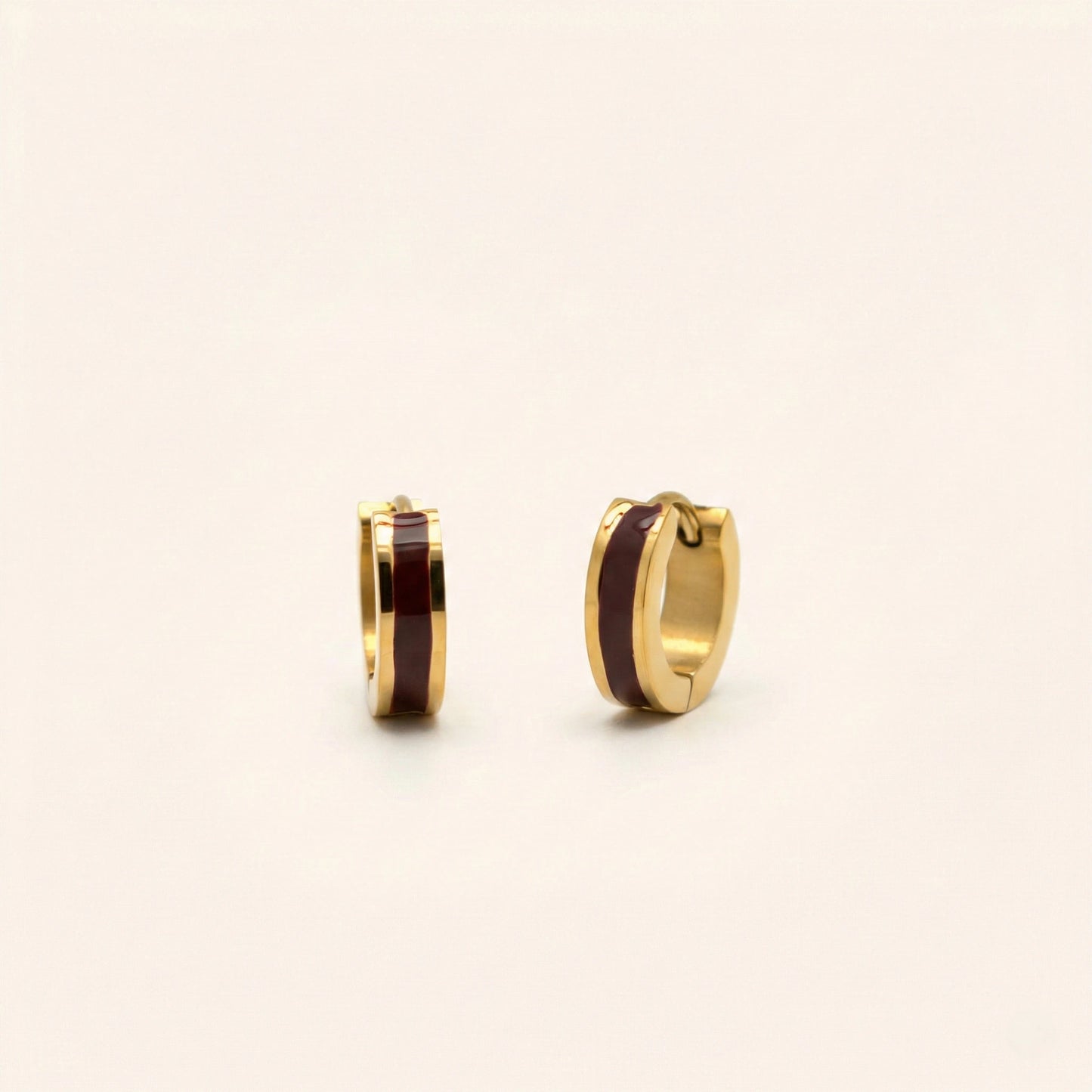 Gold hoop earrings with brown center on a light beige background